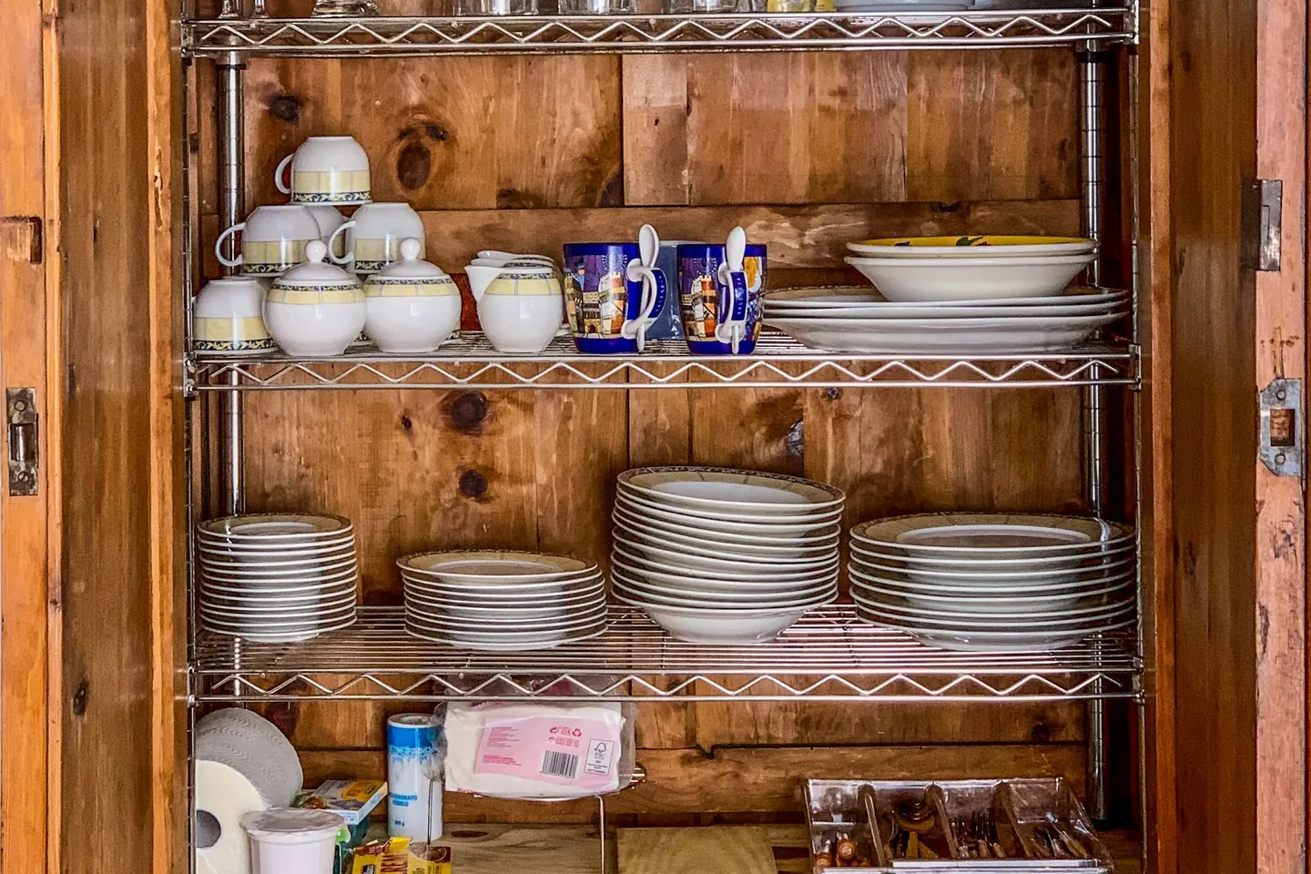 Open kitchen cabinet with neatly stacked dishes and glassware.