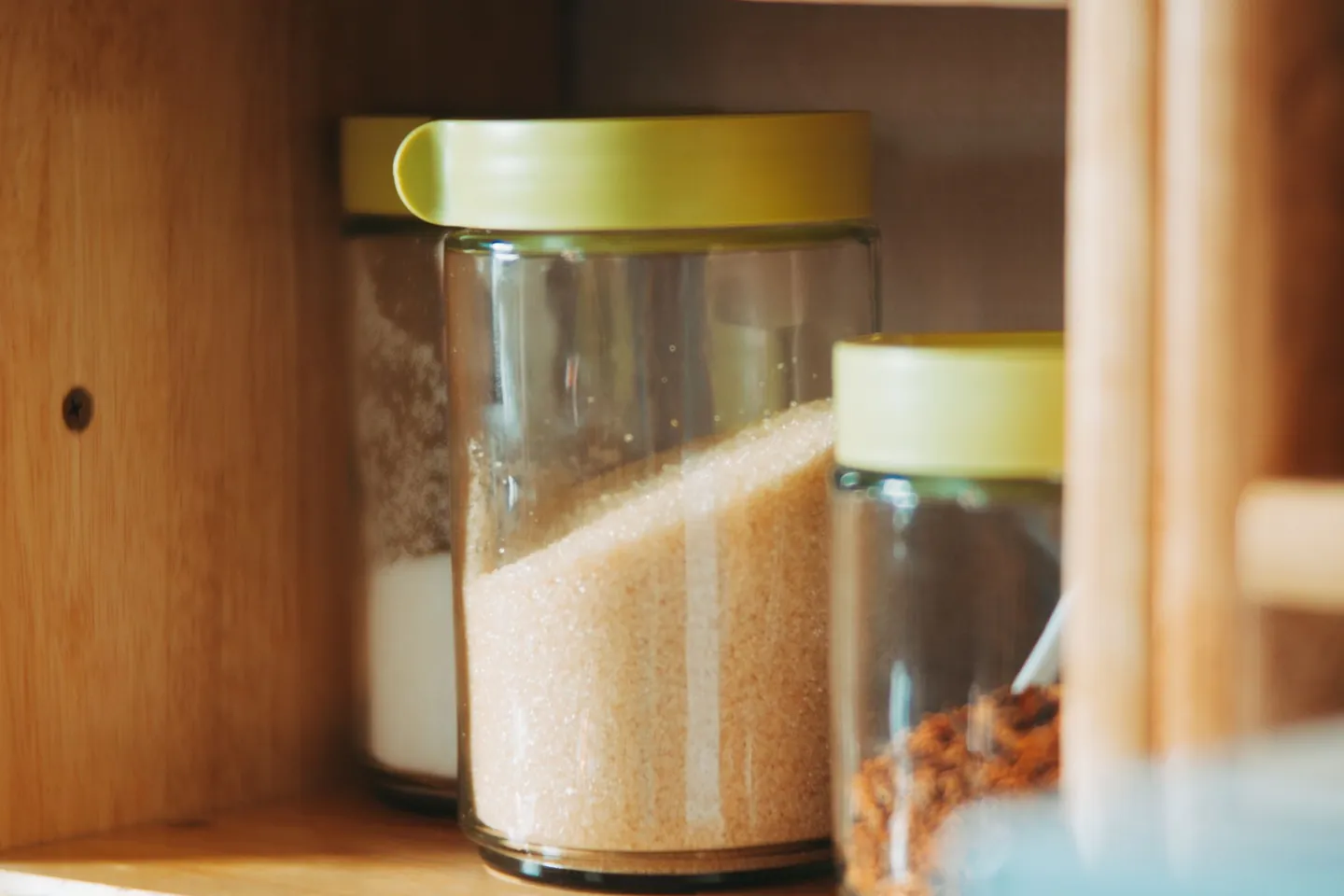 Glass jars of dry ingredients on shelves in a home pantry.